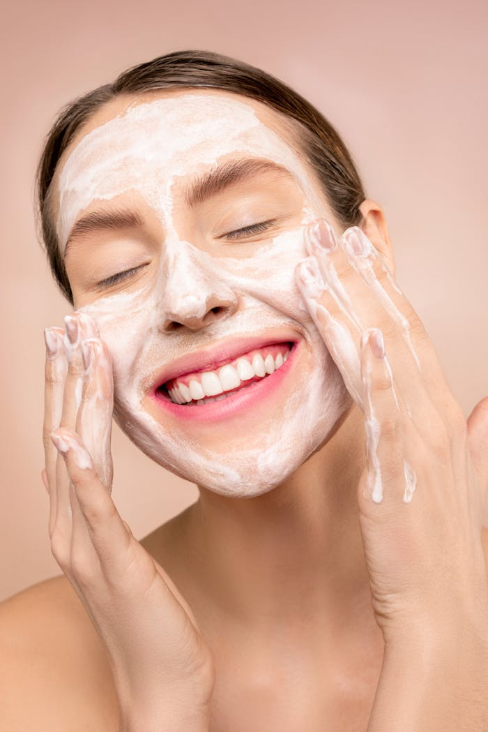 Skincare Confidence | Build Your Glow with Beautiful by Suzie Smiling woman applies facial wash while enjoying her skincare routine, promoting happiness and skin health.